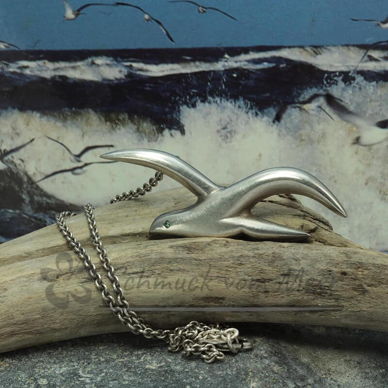 Halskette Möwe silber matt mit blauem Diamanten als Auge an Ankerkette vor Ostseewellen
