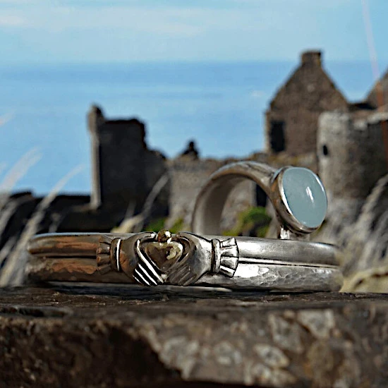 Armreif Claddagh mit Ring uisce vor irischem Castle am Atlantik